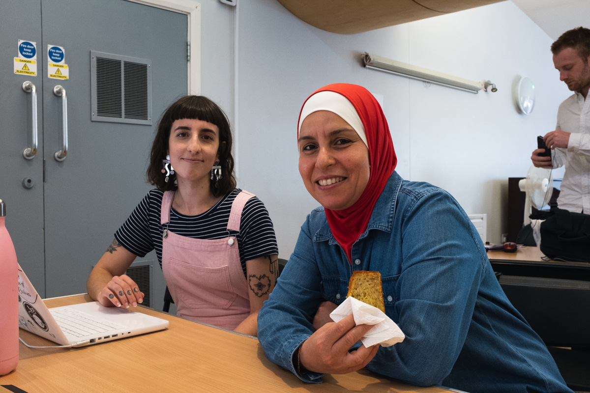 Female sits next to female refugee wearing a hijab