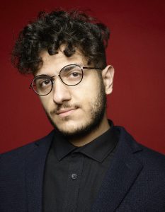 Portrait on young man wearing glasses against a red background